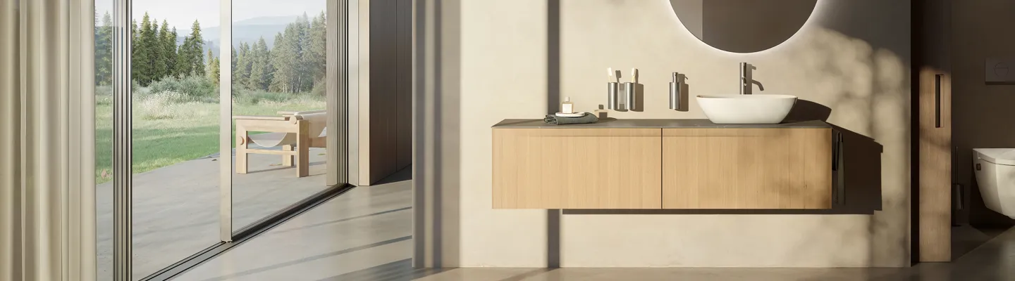 Bright, minimalist bathroom with a floating wooden vanity, white basin and round mirror; large glass doors open to a sunlit garden with trees.