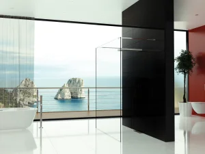 Minimalist bathroom with white floor, freestanding tub left, glass shower panel, black pillar, red wall, and a sea view with rocky formations outside.