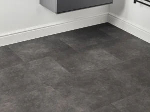 Dark grey stone-look floor tiles in a white room corner, with a floating grey cabinet above and a black towel rack to the right.