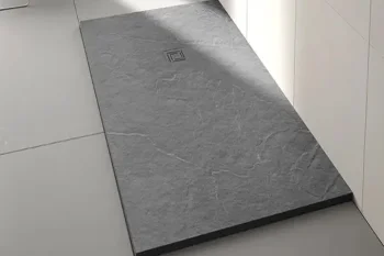 Rectangular dark grey stone slab placed on a light tiled kitchen floor beside white cabinets, featuring a small square drain near its centre.