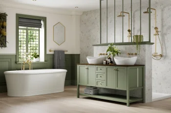 Elegant bathroom with a white freestanding tub, sage-green wainscoting, a double vessel sink vanity, brass fixtures, plants, and a textured stone shower wall.