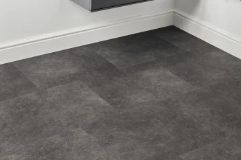 Dark grey stone-look floor tiles in a white room corner, with a floating grey cabinet above and a black towel rack to the right.
