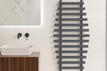 Minimalist bathroom with a white rectangular sink on a ribbed wooden vanity, black wall-mounted tap, tall grey ladder-style towel radiator, and pale grooved tiles.