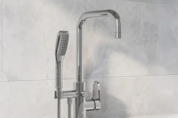 Chrome bathroom mixer with a tall curved spout, wall-mounted shower head and handheld spray beside a white bathtub on marble tiles.