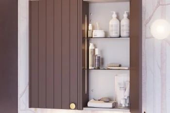Brown wall cabinet with one door open, revealing bathroom shelves of white pump bottles, jars, a brush and folded towels.