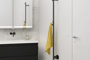 Modern bathroom with white sink on a black vanity, black wall faucet, LED mirrored cabinets, tile wall, and tall black towel rack with a yellow towel.