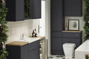 Contemporary bathroom with dark navy cabinets, white tiled walls, a wooden counter sink, toilet, and a black-and-white patterned floor framed by lush greenery.