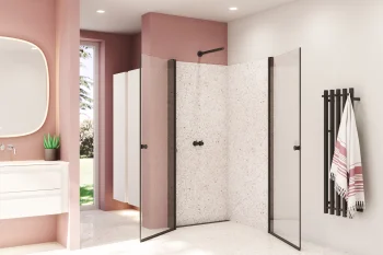 Bright pink-walled bathroom with a white vanity, backlit mirror, terrazzo shower walls, glass doors, and a black towel rail with a striped towel.
