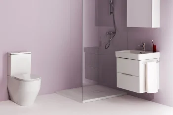 Modern lavender bathroom with a white toilet, a glass-walled shower, and a wall-mounted vanity with a towel, mirror cabinet, and a red toothbrush holder.