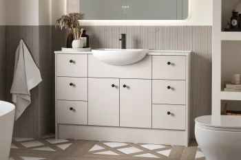 Modern bathroom with a white vanity, round vessel sink, black faucet, backlit mirror, ribbed tile backsplash, and a vase of dried grasses with towels and toiletries.