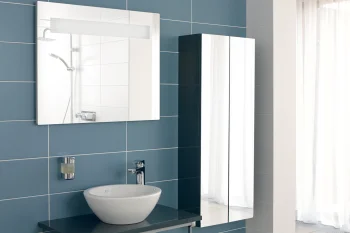 Blue tiled wall, white vessel sink on a dark blue counter with chrome tap; towel hanging below and a mirrored cabinet, shower visible in the mirror.