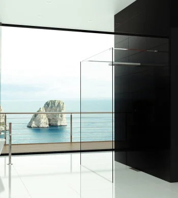 Minimalist bathroom with white floor, freestanding tub left, glass shower panel, black pillar, red wall, and a sea view with rocky formations outside.