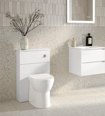 Minimalist white bathroom with wall-mounted vanity and sink, floating storage drawers, terrazzo walls and floor, a backlit mirror, vase with branches and a window.