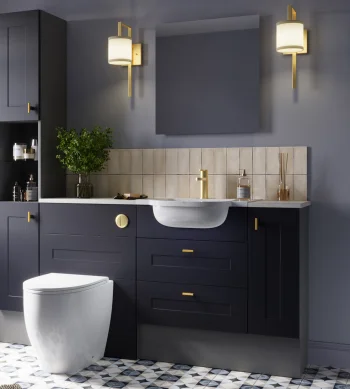 Modern navy bathroom with gold hardware, white basin, matching vanity, beige tile backsplash, wall sconces, plant, wicker hamper and patterned floor.