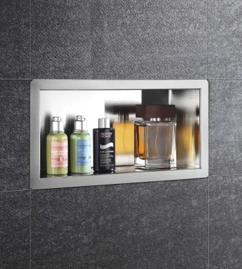 Recessed stainless shelf in dark tile wall with two green L’Occitane bottles, a Biotherm Homme bottle, and a Dolce & Gabbana perfume.