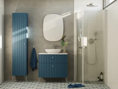 Modern bathroom with blue vertical-panel cabinetry, a blue vanity with a white vessel sink, round mirror, vase of flowers, and a glass shower; patterned tiled floor.