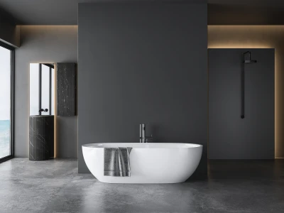 Minimalist dark-grey bathroom with a white freestanding tub and chrome taps. Grey towel over tub; left windows and a walk-in shower.