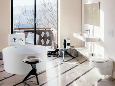 Bright, modern bathroom with a freestanding white bathtub by a large window overlooking a balcony and mountains; wall sink, mirror, and shelves.