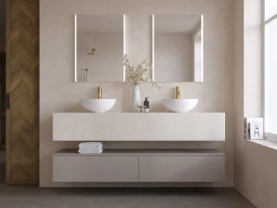 Minimalist bathroom with a floating beige vanity, twin white vessel sinks, gold taps, backlit mirrors, a vase of dried branches, and a wood wall.