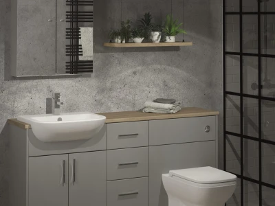 Modern grey bathroom with concrete walls, a wooden-top grey vanity, white sink, drawers, towel rail, plant shelf, toilet, and a glass-framed shower.