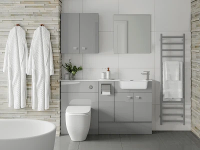 Modern grey bathroom with a stone accent wall, two white bathrobes hanging, grey cabinetry, white sink and toilet, mirror, and a ladder towel rack with towels.