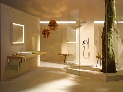 Modern wooden bathroom with glass enclosure around a tree trunk, warm lighting, floating sink, illuminated mirror, and a hammock in the corner.
