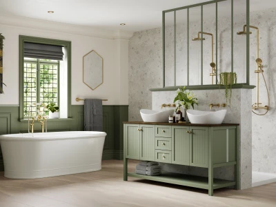 Elegant bathroom with a white freestanding tub, sage-green wainscoting, a double vessel sink vanity, brass fixtures, plants, and a textured stone shower wall.