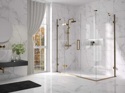 Luxurious white marble bathroom with a glass shower enclosure and brass fittings, a dark vanity with a vessel sink, potted plant, and a large window with beige curtains.