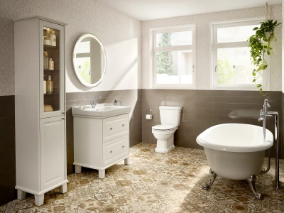 Bright bathroom with white vanity, tall cabinet, round mirror, toilet, clawfoot tub, patterned floor tiles, and a hanging plant by windows.