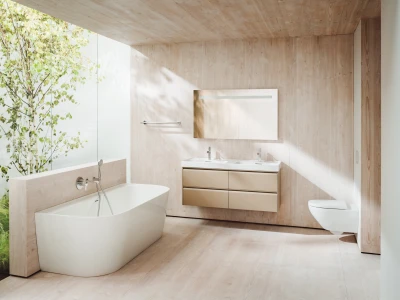 Bright bathroom with light wood panels, a white freestanding tub, beige floating vanity with double sinks, and a glass wall with a tree outside.