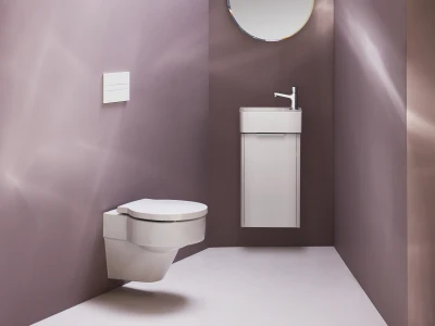 Minimalist bathroom with purple walls, a wall-mounted toilet on the left, a slim white vanity sink on the right, and a round mirror above.