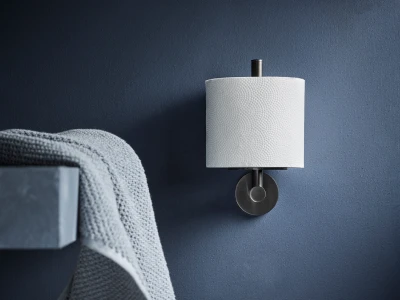 Deep blue wall with a wall-mounted metal sconce and a white textured lampshade; a grey knitted towel draped over a nearby shelf.