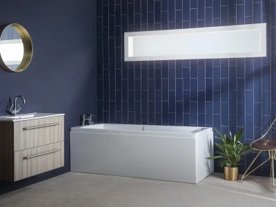 Contemporary bathroom with dark navy walls and a navy tile wall, white freestanding tub, wood vanity with chrome taps, round gold mirror, gold wire chair and a potted plant.