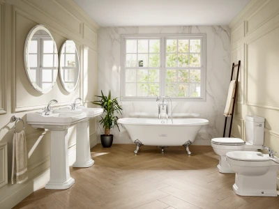 Bright bathroom with a freestanding clawfoot tub by a large window, two pedestal sinks with mirrors, marble walls, a plant and a herringbone floor.