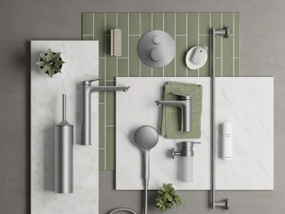 Flat lay of bathroom fixtures: brushed metal taps, handheld shower, soap dispenser, green towel, and plants on a green tile backdrop with marble slabs.