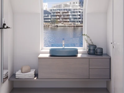 Minimalist bathroom with a blue oval basin on a light wood floating vanity, large window overlooking harbour and buildings, decorative vases, plant, towels and soap on display.