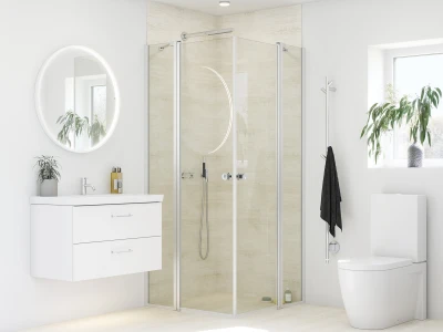 Bright modern bathroom with circular backlit mirror, white vanity with two drawers, glass-framed shower, toilet, and a plant by the window.