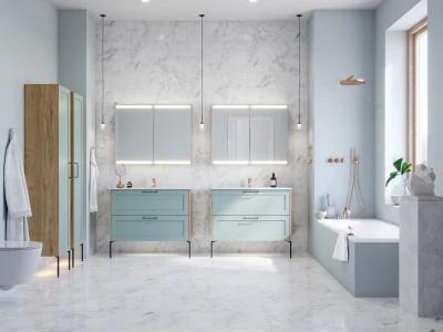 Modern bathroom with pale blue vanities, marble walls and floor, backlit mirrors, gold fixtures, a bathtub by a window and a tall wooden cabinet.