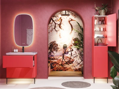 Pink bathroom with a coral vanity and white sink, backlit oval mirror, an arched mural of cranes, and a pink cabinet with toiletries; plants and rugs.
