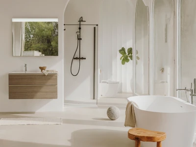 Bright, minimalist bathroom with a floating wooden vanity, black shower system, glass enclosure, freestanding tub, arched niches, plant and stool.