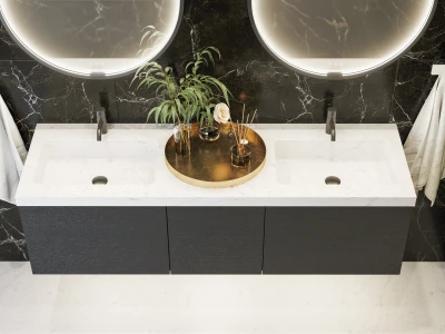 Double white marble sink vanity in a black marble bathroom, with circular backlit mirrors, a gold tray of plants and diffusers, and towels on either side.