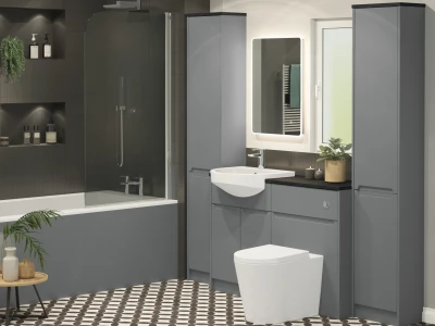 Modern grey bathroom with tall cabinets, backlit mirror, white sink, glass shower panel, toilet and patterned floor tiles with a potted plant.