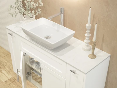 White bathroom vanity with marble top and a rectangular white vessel sink, chrome tap, a vase of white blossoms, two tall candles, and a woven basket on the lower shelf.
