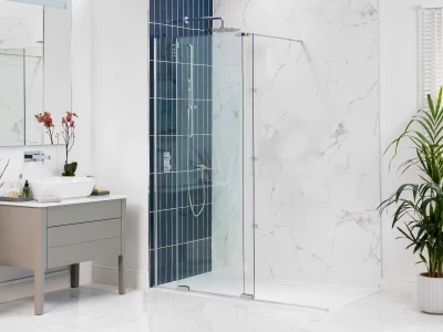 Modern bathroom with a glass shower enclosure and blue tiles, marble walls, a grey vanity with a round sink and orchid, and a tall plant by window.