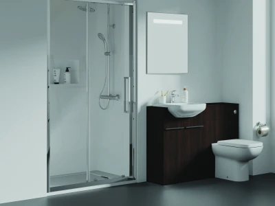 Modern bathroom with a glass shower enclosure, dark wood vanity and white sink, wall mirror, and a toilet against pale blue walls.