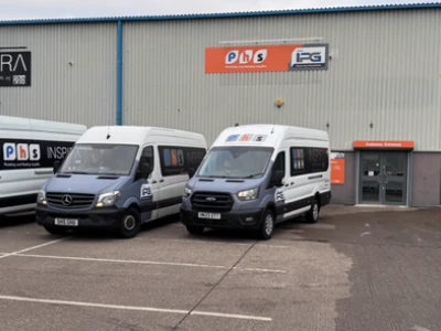 Three white DPD delivery vans parked outside an industrial building with "INSPIRA" signage and green loading doors.
