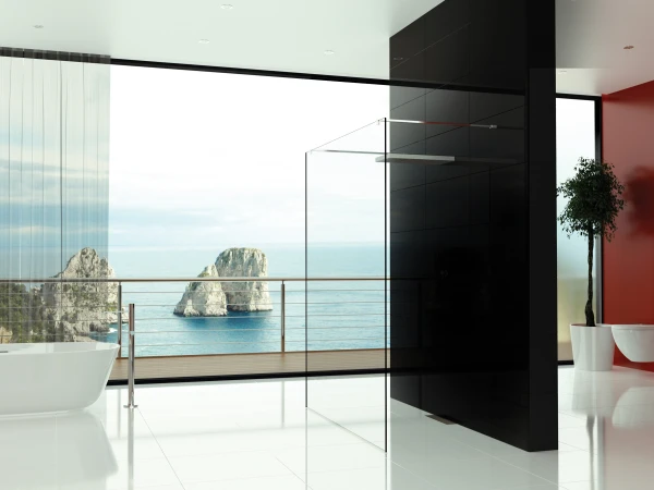 Minimalist bathroom with white floor, freestanding tub left, glass shower panel, black pillar, red wall, and a sea view with rocky formations outside.