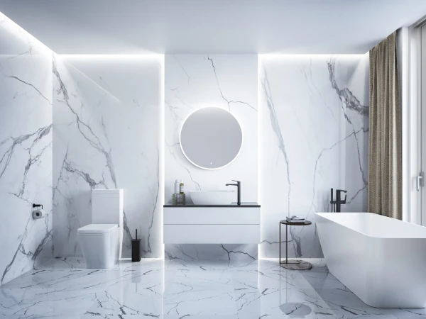 Luxurious marble bathroom with veined white walls and floor, a freestanding bathtub by large windows, and a floating vanity with a circular backlit mirror.