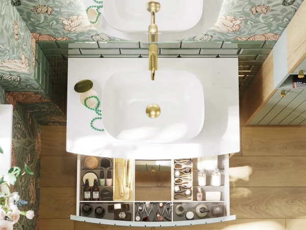Top-down view of a bathroom vanity with two white basins, gold taps, marble counter, green floral wallpaper, and open cosmetic drawers.