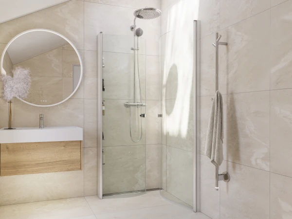 Beige-tiled bathroom with a round mirror above a white sink on a wood vanity, a glass shower enclosure with rain head, and a chrome towel rail.